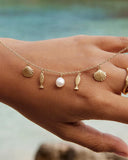 Gold plated charm necklace with shell, fish and natural pearl pendants on a delicate chain, inspired by Mediterranean summer style — επιχρυσωμένο κολιέ με charms κοχύλι, ψαράκι και φυσικό μαργαριτάρι σε λεπτή αλυσίδα, εμπνευσμένο από το καλοκαιρινό μεσογειακό στυλ. Διαθέσιμο στο Iconic Angels Glyfada.