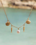 Gold plated charm necklace with shell, fish and natural pearl pendants on a delicate chain, inspired by Mediterranean summer style — επιχρυσωμένο κολιέ με charms κοχύλι, ψαράκι και φυσικό μαργαριτάρι σε λεπτή αλυσίδα, εμπνευσμένο από το καλοκαιρινό μεσογειακό στυλ. Διαθέσιμο στο Iconic Angels Glyfada.