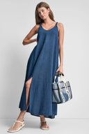 Blue denim-effect maxi dress with thin straps, V-neckline and front slit detail, combining relaxed silhouette with feminine summer elegance — μπλε maxi φόρεμα με denim υφή, λεπτές τιράντες, V ντεκολτέ και μπροστινό σκίσιμο, ιδανικό για island, vacation και casual chic looks. Διαθέσιμο στο Iconic Angels Glyfada.