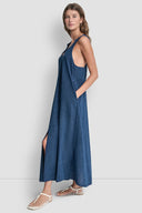 Blue denim-effect maxi dress with thin straps, V-neckline and front slit detail, combining relaxed silhouette with feminine summer elegance — μπλε maxi φόρεμα με denim υφή, λεπτές τιράντες, V ντεκολτέ και μπροστινό σκίσιμο, ιδανικό για island, vacation και casual chic looks. Διαθέσιμο στο Iconic Angels Glyfada.