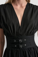Black midi cotton dress with deep V-neckline, short wide sleeves and structured waist with double buckle belt detail, combining feminine silhouette with modern edge — μαύρο midi φόρεμα με V ντεκολτέ, κοντά φαρδιά μανίκια και ζώνη με διπλή αγκράφα στη μέση, ιδανικό για elegant day to night looks. Διαθέσιμο στο Iconic Angels Glyfada.