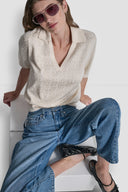 Cream short-sleeve knit polo top with subtle all-over DKNY monogram pattern, V-neckline and structured collar, blending elevated minimal style with everyday comfort — εκρού πλεκτό polo top με διακριτικό DKNY monogram, V ντεκολτέ και γιακά, ιδανικό για chic casual και smart day looks. Διαθέσιμο στο Iconic Angels Glyfada.