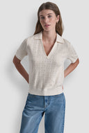 Cream short-sleeve knit polo top with subtle all-over DKNY monogram pattern, V-neckline and structured collar, blending elevated minimal style with everyday comfort — εκρού πλεκτό polo top με διακριτικό DKNY monogram, V ντεκολτέ και γιακά, ιδανικό για chic casual και smart day looks. Διαθέσιμο στο Iconic Angels Glyfada.