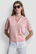 Pink short-sleeve knit polo top with subtle all-over DKNY monogram pattern, V-neckline and classic collar, combining feminine elegance with modern minimal style — ροζ πλεκτό polo top με διακριτικό DKNY monogram, V ντεκολτέ και γιακά, ιδανικό για chic casual και polished day looks. Διαθέσιμο στο Iconic Angels Glyfada.