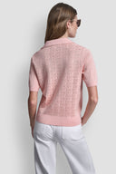 Pink short-sleeve knit polo top with subtle all-over DKNY monogram pattern, V-neckline and classic collar, combining feminine elegance with modern minimal style — ροζ πλεκτό polo top με διακριτικό DKNY monogram, V ντεκολτέ και γιακά, ιδανικό για chic casual και polished day looks. Διαθέσιμο στο Iconic Angels Glyfada.