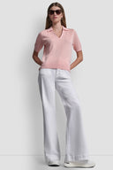 Pink short-sleeve knit polo top with subtle all-over DKNY monogram pattern, V-neckline and classic collar, combining feminine elegance with modern minimal style — ροζ πλεκτό polo top με διακριτικό DKNY monogram, V ντεκολτέ και γιακά, ιδανικό για chic casual και polished day looks. Διαθέσιμο στο Iconic Angels Glyfada.