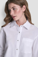 White long-sleeve button-down shirt with classic collar, front pocket and clean structured silhouette, offering timeless minimal elegance for versatile styling — λευκό γυναικείο πουκάμισο με κουμπιά, γιακά και μπροστινή τσέπη, ιδανικό για office chic και smart casual looks με refined χαρακτήρα. Διαθέσιμο στο Iconic Angels Glyfada.