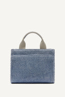 DKNY Hadlee Small Logo Tote σε γαλάζιο ψάθινο σχέδιο με λευκό λογότυπο “DKNY New York”, διπλά κοντά χερούλια και ρυθμιζόμενο λουρί ώμου. Ιδανική καλοκαιρινή tote τσάντα για καθημερινά city looks και resort εμφανίσεις. Διαθέσιμη στο Iconic Angels.
