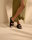 Suede Nordic sandals in classic black with satin gold buckles and a natural jute footbed, combining timeless elegance with everyday comfort — μαύρα suede Nordic σανδάλια με σατινέ χρυσές αγκράφες και φυσικό πάτο από σχοινί, ιδανικά για effortless chic εμφανίσεις που φοριούνται από το πρωί έως το βράδυ. Διαθέσιμα στο Iconic Angels Glyfada.