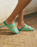Women’s suede slide sandals in pastel green with double buckle straps, γυναικεία σανδάλια slides από suede δέρμα σε παστέλ πράσινη απόχρωση, άνετα και statement για καλοκαιρινές εμφανίσεις, από το Iconic Angels Glyfada.