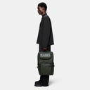 Cargo-style green backpack with bold RAINS logo, multiple zip compartments and structured silhouette, functional and modern for everyday use or travel — πράσινο backpack cargo με έντονο λογότυπο RAINS, πολλαπλές θήκες με φερμουάρ και δομημένο σχήμα, πρακτικό και σύγχρονο για καθημερινές εμφανίσεις ή ταξίδια. Διαθέσιμο στο Iconic Angels Glyfada.