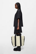 Cream waterproof tote bag with contrast black straps, structured and spacious, perfect for city days and weekend escapes — κρεμ αδιάβροχη tote τσάντα με μαύρα λουριά σε αντίθεση, minimal και ευρύχωρη, ιδανική για busy καθημερινότητα αλλά και σύντομες αποδράσεις. Διαθέσιμη στο Iconic Angels Glyfada.