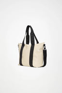 Cream waterproof tote bag with contrast black straps, structured and spacious, perfect for city days and weekend escapes — κρεμ αδιάβροχη tote τσάντα με μαύρα λουριά σε αντίθεση, minimal και ευρύχωρη, ιδανική για busy καθημερινότητα αλλά και σύντομες αποδράσεις. Διαθέσιμη στο Iconic Angels Glyfada.