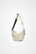 Cream glossy shoulder bag with curved silhouette and adjustable strap, minimalist and versatile, perfect for effortless everyday styling — κρεμ γυαλιστερή shoulder τσάντα με καμπύλη γραμμή και ρυθμιζόμενο λουρί, minimal και ευκολοφόρετη, ιδανική για κομψά daily looks από το πρωί έως το βράδυ. Διαθέσιμη στο Iconic Angels Glyfada.