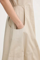 Beige sleeveless midi dress with clean round neckline, fitted waist and flared skirt with side pockets, combining minimal elegance with effortless structure — μπεζ αμάνικο midi φόρεμα με καθαρή λαιμόκοψη, τονισμένη μέση και άνετη φούστα με τσέπες, ιδανικό για office chic και refined day looks. Διαθέσιμο στο Iconic Angels Glyfada.