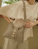 Individual Art Leather Emalene Stone beige τσάντα ώμου από πλεκτό δέρμα με διάτρητο σχέδιο, διακοσμητικό λουράκι με μεταλλικά στοιχεία και ρυθμιζόμενο strap, ιδανική για chic καθημερινά looks.