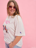 White oversized graphic T-shirt from Project Soma x Barbie collection with “Makin’ Things Happen” print and Barbie imagery for playful statement styling — λευκό oversized γυναικείο t-shirt Project Soma x Barbie με graphic print “Makin’ Things Happen” και Barbie φωτογραφίες για μοντέρνα casual looks. Διαθέσιμο στο Iconic Angels Glyfada.