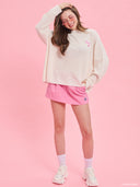 Off-white oversized knit sweater from Project Soma x Barbie collection with embroidered Barbie logo and relaxed silhouette for cozy modern styling — εκρού oversized πλεκτό γυναικείο πουλόβερ Project Soma x Barbie με κεντημένο Barbie logo και άνετη γραμμή για μοντέρνα casual looks. Διαθέσιμο στο Iconic Angels Glyfada.