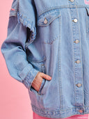 Oversized light blue denim jacket from Project Soma x Barbie collection with pink embroidered Barbie logo and statement streetwear aesthetic — oversized γυναικείο τζιν jacket σε ανοιχτό μπλε από τη συλλογή Project Soma x Barbie, με ροζ κεντημένο Barbie logo και μοντέρνο streetwear χαρακτήρα. Διαθέσιμο στο Iconic Angels Glyfada.