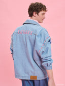 Oversized light blue denim jacket from Project Soma x Barbie collection with pink embroidered Barbie logo and statement streetwear aesthetic — oversized γυναικείο τζιν jacket σε ανοιχτό μπλε από τη συλλογή Project Soma x Barbie, με ροζ κεντημένο Barbie logo και μοντέρνο streetwear χαρακτήρα. Διαθέσιμο στο Iconic Angels Glyfada.