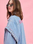 Oversized light blue denim jacket from Project Soma x Barbie collection with pink embroidered Barbie logo and statement streetwear aesthetic — oversized γυναικείο τζιν jacket σε ανοιχτό μπλε από τη συλλογή Project Soma x Barbie, με ροζ κεντημένο Barbie logo και μοντέρνο streetwear χαρακτήρα. Διαθέσιμο στο Iconic Angels Glyfada.