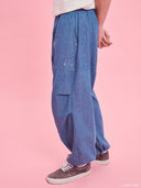 Blue denim balloon pants from Project Soma x Barbie collection with elastic waist and relaxed streetwear silhouette — γυναικείο denim παντελόνι balloon από τη συλλογή Project Soma x Barbie με λάστιχο στη μέση και χαλαρή streetwear γραμμή για statement casual looks. Διαθέσιμο στο Iconic Angels Glyfada.