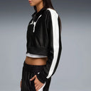 Black cropped track jacket with contrast white side stripes and bold Puma logo detail, combining retro sport heritage with modern streetwear appeal — μαύρο γυναικείο cropped track jacket με λευκές ρίγες στα μανίκια και statement logo μπροστά, ιδανικό για athleisure και street style looks με δυναμικό χαρακτήρα. Διαθέσιμο στο Iconic Angels Glyfada.