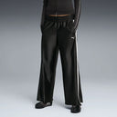 Black wide leg track pants with contrast white side stripes and bold Puma logo detail on the back, combining retro sport heritage with modern streetwear appeal — μαύρο γυναικείο παντελόνι φόρμας σε wide leg γραμμή με λευκές ρίγες στο πλάι και statement logo πίσω, ιδανικό για athleisure και street style looks. Διαθέσιμο στο Iconic Angels Glyfada.