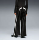 Black wide leg track pants with contrast white side stripes and bold Puma logo detail on the back, combining retro sport heritage with modern streetwear appeal — μαύρο γυναικείο παντελόνι φόρμας σε wide leg γραμμή με λευκές ρίγες στο πλάι και statement logo πίσω, ιδανικό για athleisure και street style looks. Διαθέσιμο στο Iconic Angels Glyfada.