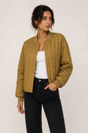 Quilted bomber jacket in warm camel tone with snap-button closure and ribbed trims — καπιτονέ bomber jacket σε ζεστή camel απόχρωση με κουμπιά και ριμπ τελειώματα για relaxed αλλά elevated ύφος. Ανάλαφρο, άνετο και ιδανικό για layering, δίνει σύγχρονο χαρακτήρα σε κάθε casual look, από denim μέχρι tailored παντελόνια. Το τέλειο transitional κομμάτι για καθημερινές εμφανίσεις με urban αισθητική. Διαθέσιμο στο Iconic Angels Glyfada.