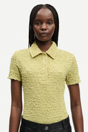 Light olive textured polo top with short sleeves, button placket and fitted silhouette, offering a refined casual feel — λαχανί κοντομάνικο polo top με κουμπιά και ελαστική textured ύφανση, σε εφαρμοστή γραμμή ιδανική για chic casual και modern everyday looks. Διαθέσιμο στο Iconic Angels Glyfada.