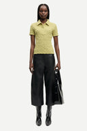 Light olive textured polo top with short sleeves, button placket and fitted silhouette, offering a refined casual feel — λαχανί κοντομάνικο polo top με κουμπιά και ελαστική textured ύφανση, σε εφαρμοστή γραμμή ιδανική για chic casual και modern everyday looks. Διαθέσιμο στο Iconic Angels Glyfada.