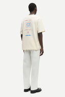 Off-white graphic t-shirt with front and back print details, featuring Samsoe Samsoe leisure lotion artwork in red and blue tones — εκρού κοντομάνικο t-shirt με logo print και summer inspired γραφικά μπροστά και πίσω, σε relaxed γραμμή ιδανική για casual και streetwear looks με playful χαρακτήρα. Διαθέσιμο στο Iconic Angels Glyfada.