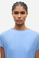 Light blue pleated short sleeve top with fluid silhouette and minimal neckline, offering soft movement and modern elegance — γαλάζιο πλισέ τοπ με κοντό μανίκι και αέρινη γραμμή, ιδανικό για chic casual, office και elevated summer looks με minimal αισθητική. Διαθέσιμο στο Iconic Angels Glyfada.