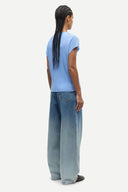 Light blue pleated short sleeve top with fluid silhouette and minimal neckline, offering soft movement and modern elegance — γαλάζιο πλισέ τοπ με κοντό μανίκι και αέρινη γραμμή, ιδανικό για chic casual, office και elevated summer looks με minimal αισθητική. Διαθέσιμο στο Iconic Angels Glyfada.